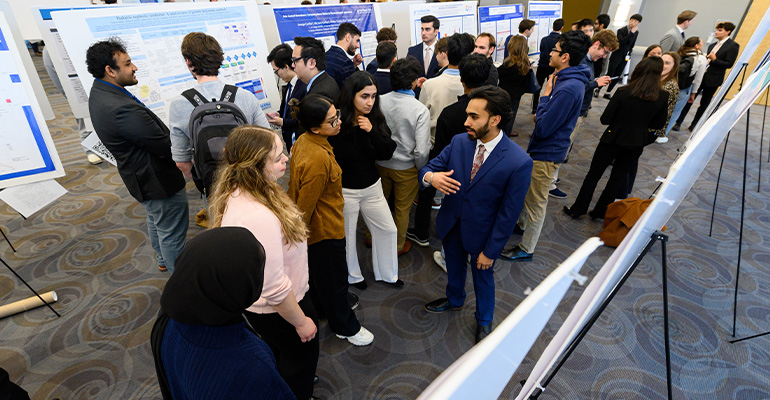 crowd of people explore academic posters in conference hall