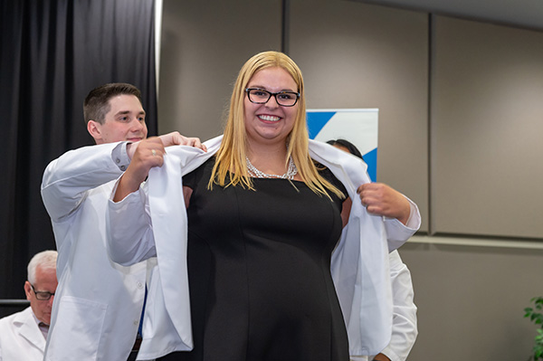 Elizabeth Olah, first-year College of Medicine student, putting on her white coat