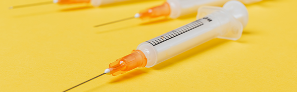 Syringe laying on flat, yellow surface.