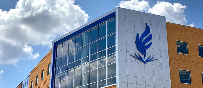 Looking up at NEOMED's iconic flame on the north side of the facility on a sunny day.