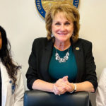 Two medicine students in white coats stand with a state representative in Columbus.
