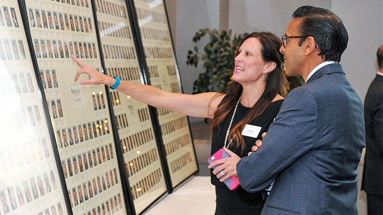 Two alumni look at a class photo from years ago.