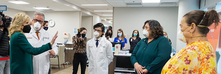 First Lady Jill Biden gestures while talking to a group of medical professionals.