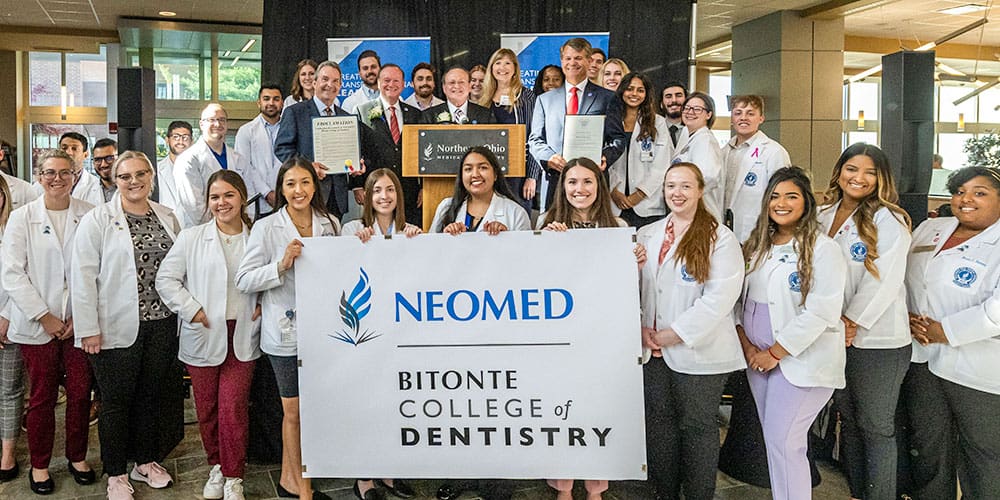 Students hold a sign printed with the words, Bitonte College of Dentistry