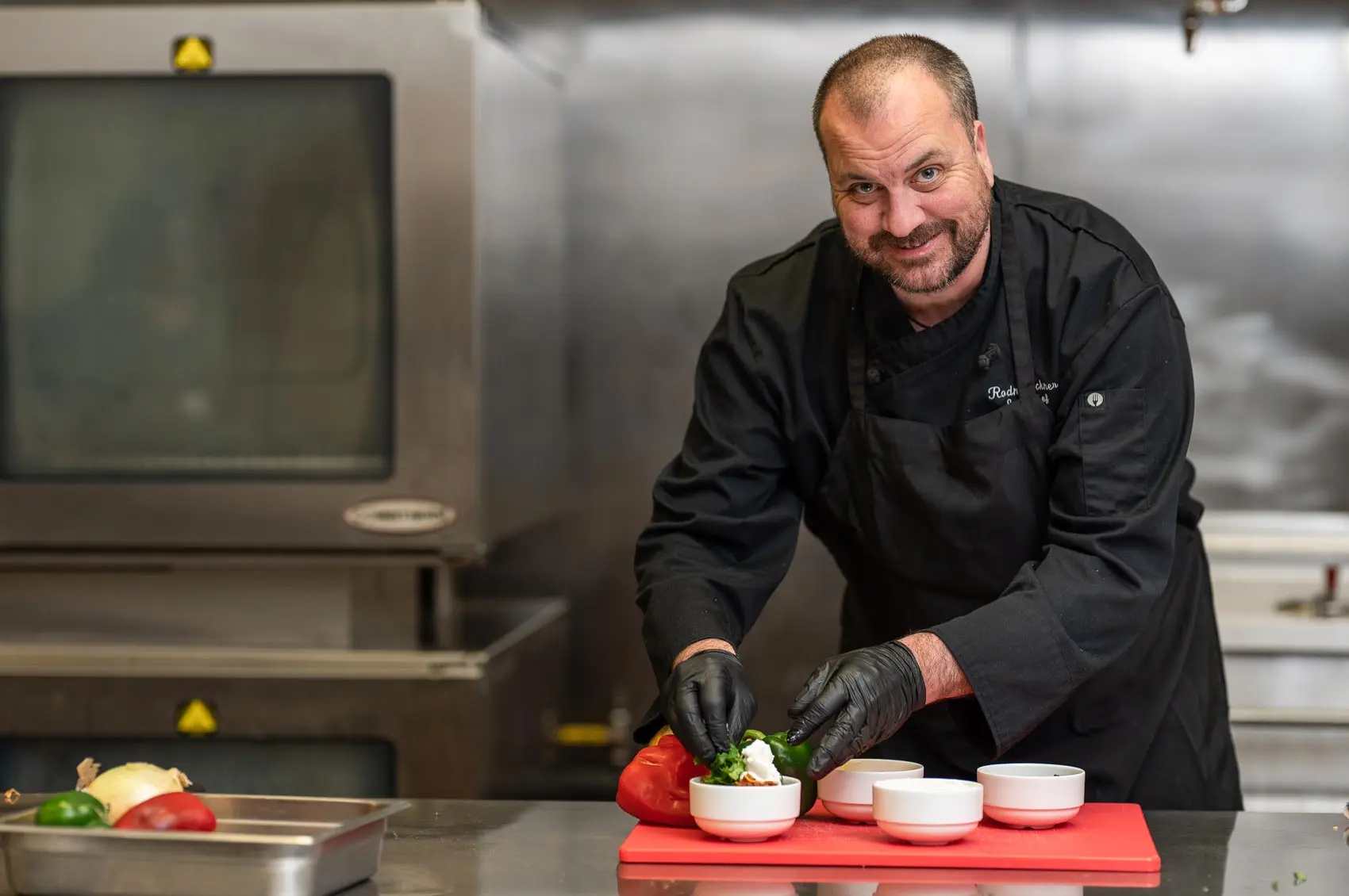 A chef in a black coat at a table.