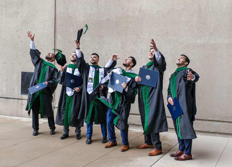 A group of graduates throw their caps into the air.