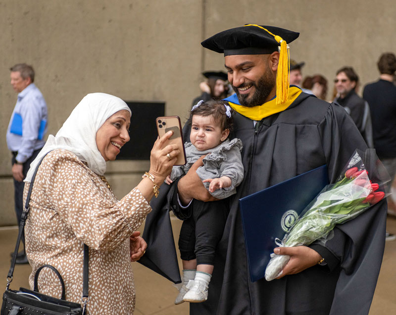 A graduate holding his infant daughter.
