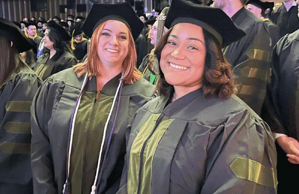 commencement-2026-10 Two pharmacy graduates smile during NEOMED's commencement ceremony.