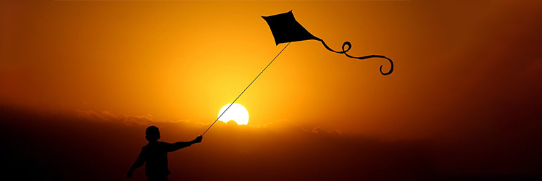 A child runs with a kite.