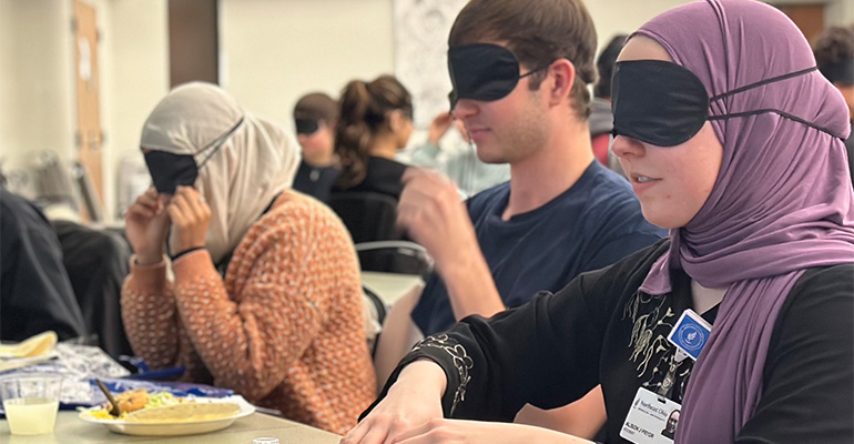 group of college students attempts to dine while wearing blindfolds