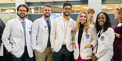 Two people in a laboratory discuss documents and equipment at a crowded workbench.