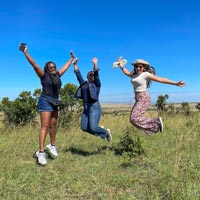 Three people jump with their arms up.