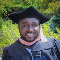 A graduate student holds his degree at Commencement.