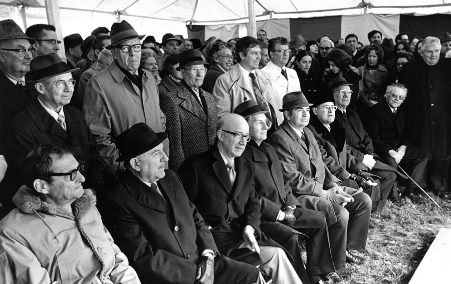 A large group of attendees poses beneath a tent during a groundbreaking ceremony.
