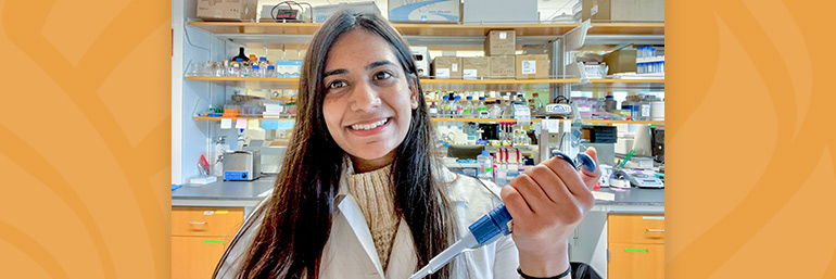 A NEOMED researcher in a laboratory with instruments behind her.