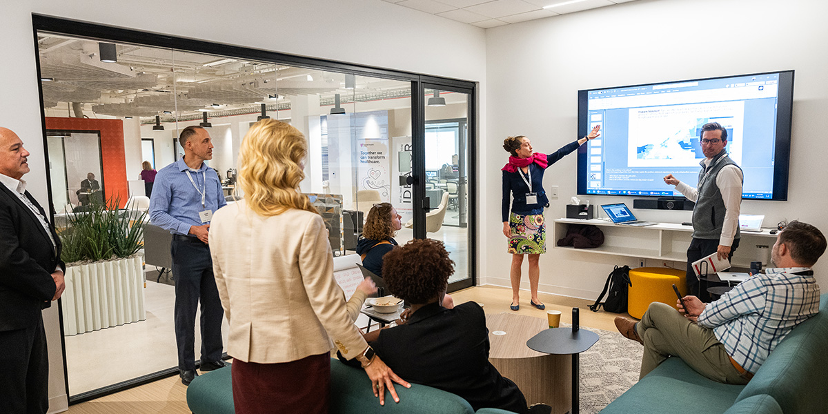 woman points to something on a presentation while teammates look on