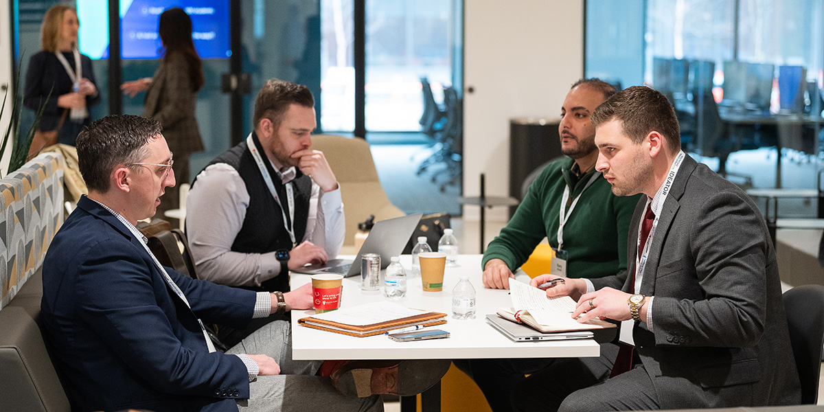 four men sit around a table in deep discussion