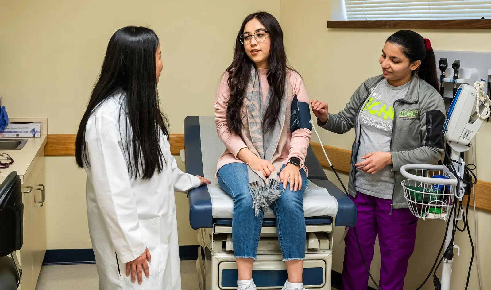 In an examination room, a young patient and her mother listen to a doctor.