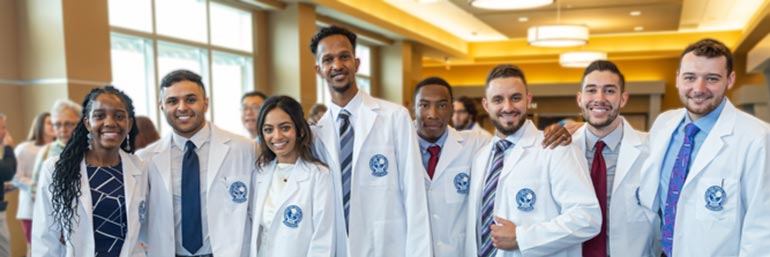 Eight medicine students stand in a row during the celebration following the ceremony.