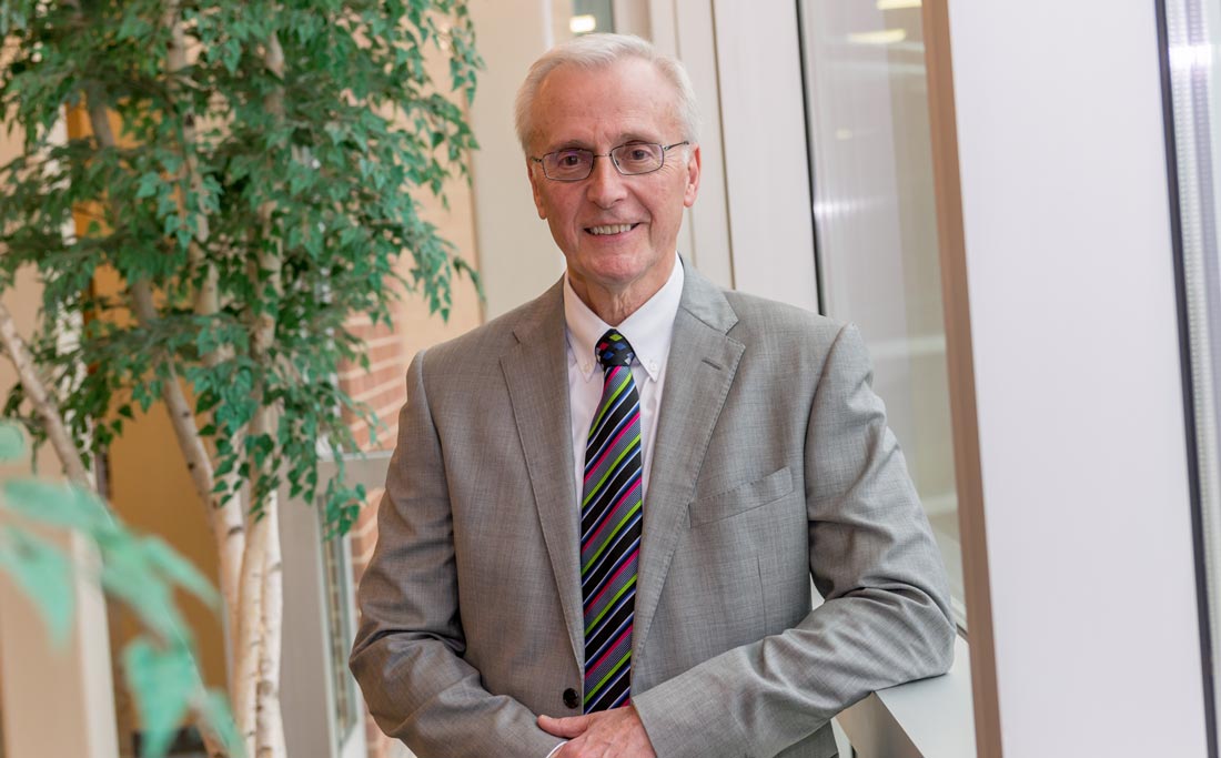 A portrait of Dr. Mikolich in a gray suit.