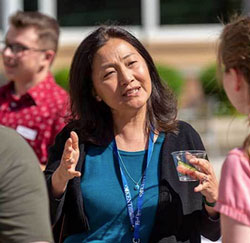 A faculty mentor gestures while talking with a NEOMED student during a campus event.