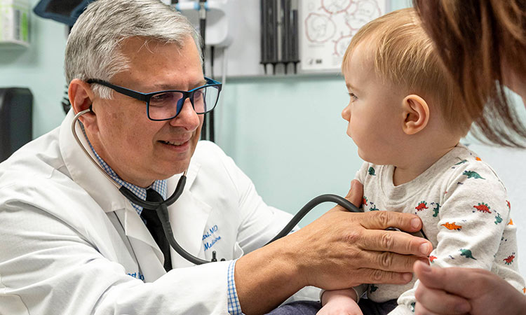A physician at NEOMED Health Care checks the heartbeat of a toddler..