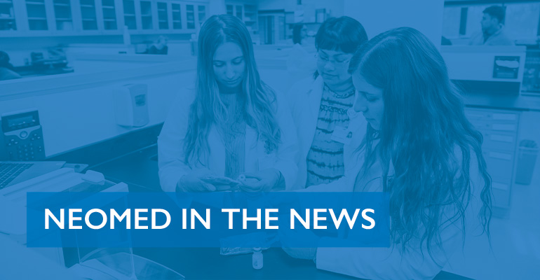 Three pharmacy students in white coats work in the lab