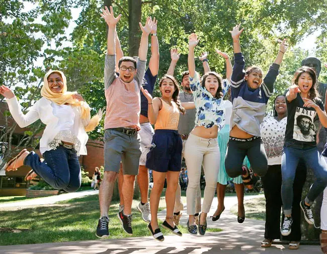 A group of NEOMED students jump at the same time, their arms extended upward.