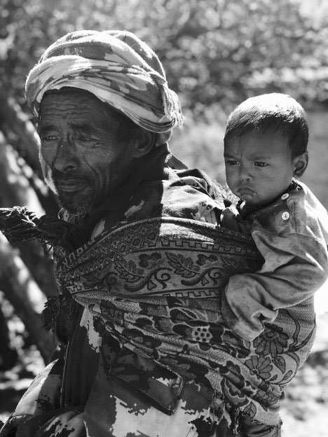 A man carries a baby on his back.