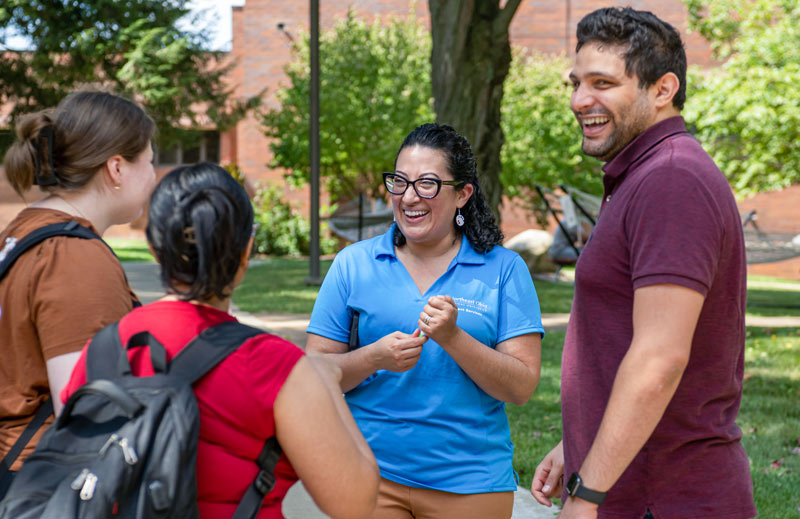 A woman chats with students in the courtyard at NEOMED during a campus event.
