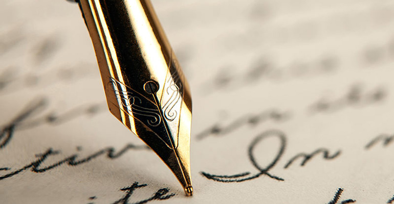 An old fashioned pen tip writes in a fancy script