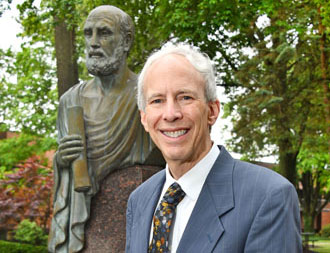 The dean of the college in a coat and tie in the courtyard at NEOMED.