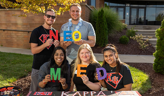 Five students hold letters spelling NEOMED.