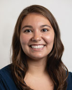 A smiling woman stands for a portrait.