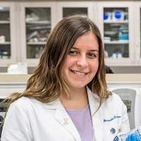 A pharmacy student in a white coat in a lab.