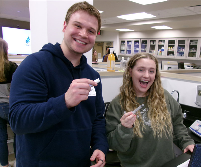 Two members of the pharmacy club hold pharmacy tools in a NEOMED lab.