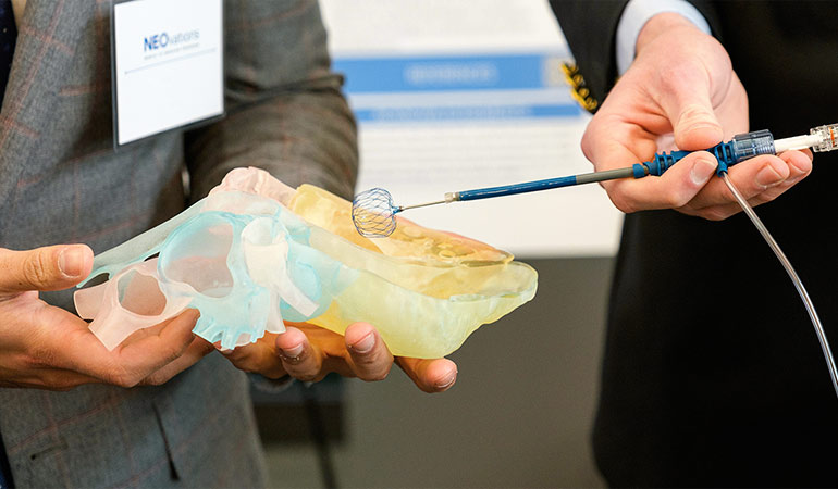 An student innovator shows off a prototype during an on-campus event for judges and investors.