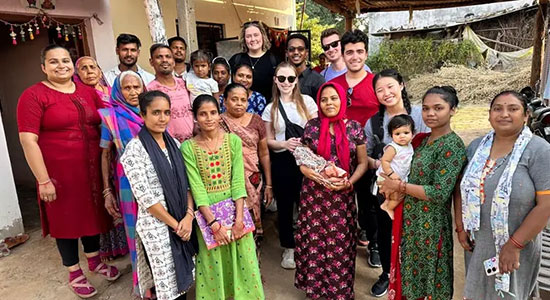 In Nepal, a group of community members and NEOMED students stand together outdoors, in a rural setting.