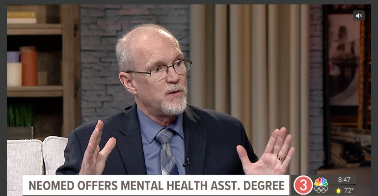 A professor gestures while talking during a television interview.
