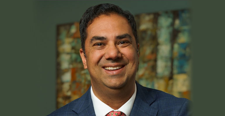 Portrait of Dr. Soin in a coat and tie, with a window in the background.