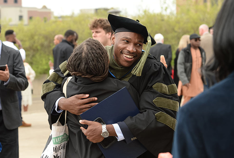 A graduate is hugged by a family member after commencement.