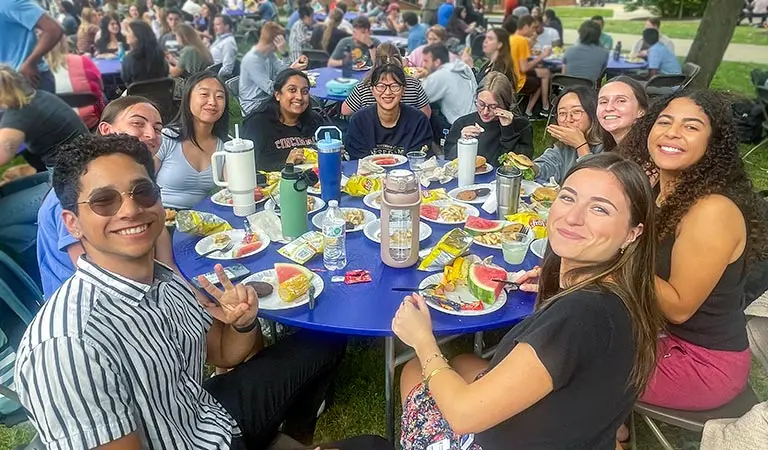 Students at a round table in the NEOMED courtyard during a university picnic.