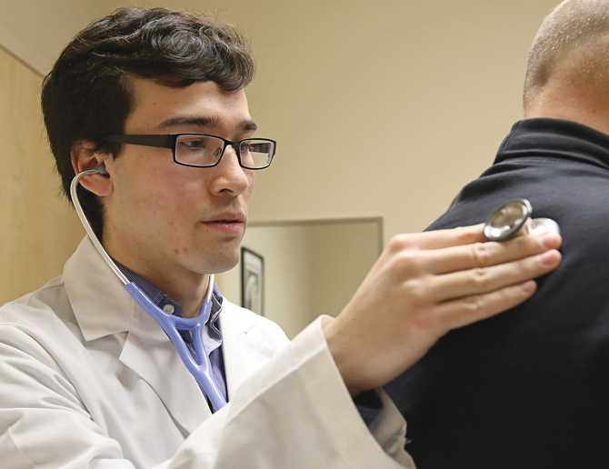 Student uses stethoscope on patient in the Student-Run Free Clinic