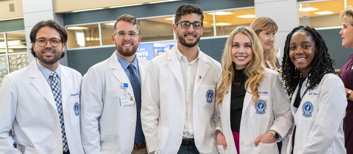 A group of NEOMED students in white coats at a ceremony.