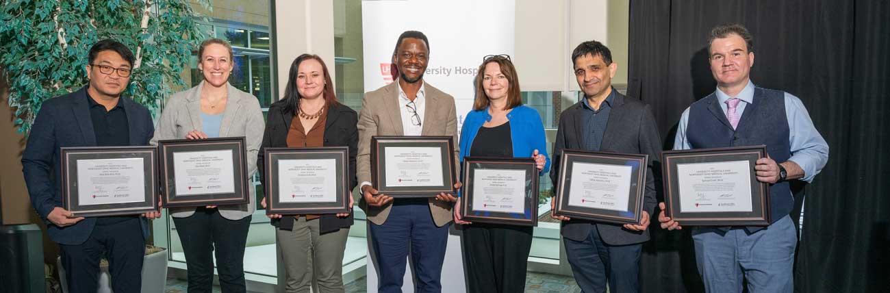 Seven UH Faculty Scholars stand for a photo, each holding a certificate.