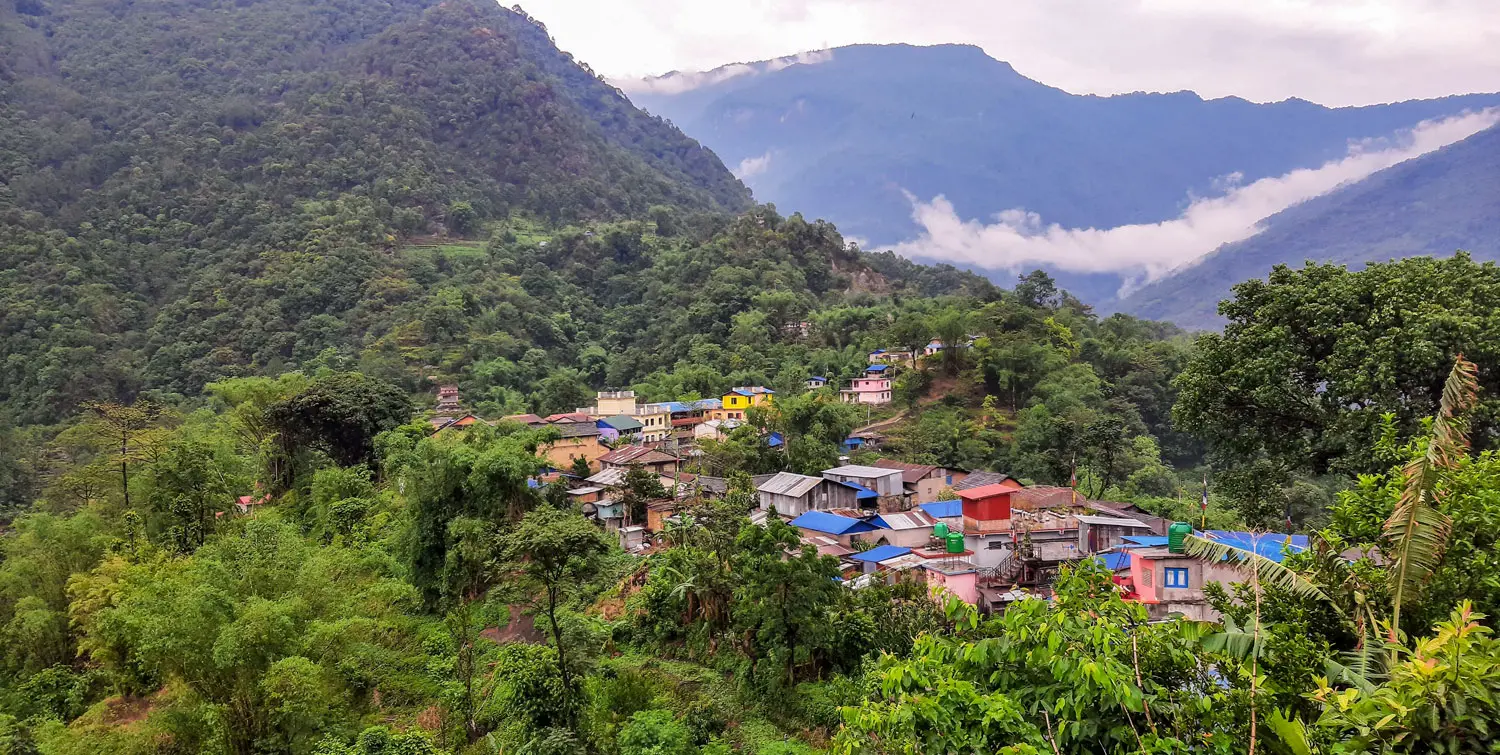 A village in Nepal, surrounded by green mountains.