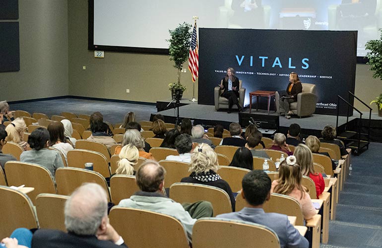 A VITALS speaker addresses an auditorium full of guests.