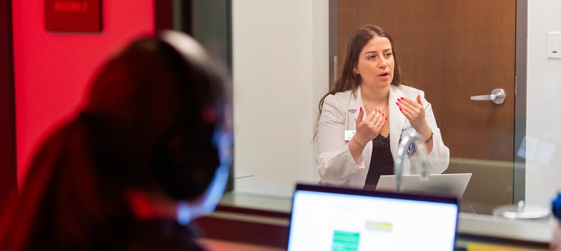 A student doctor gestures while talking with a standardized patient in NEOMED's Wasson Center.