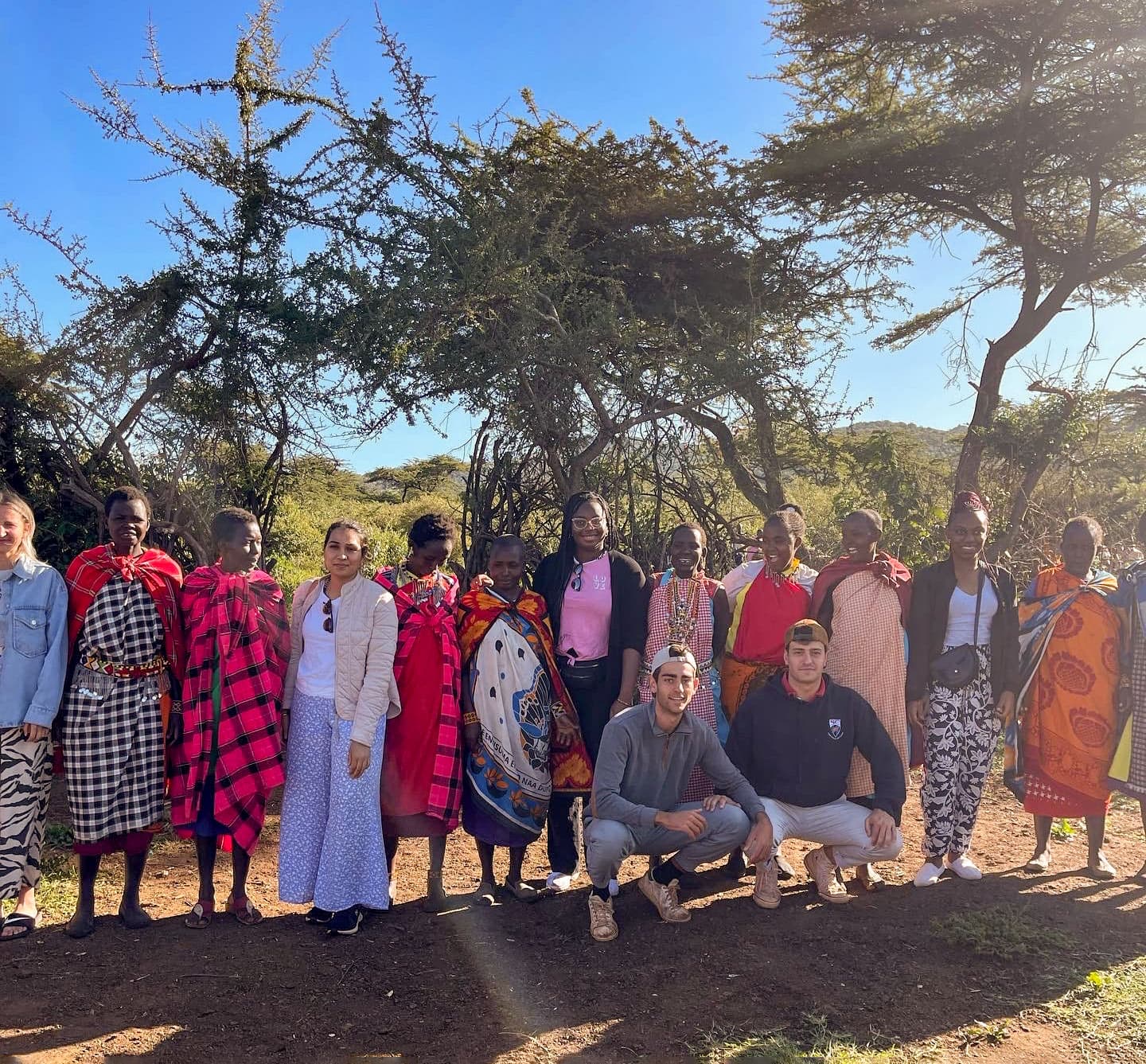 A group of people in an arid location with trees in the background.